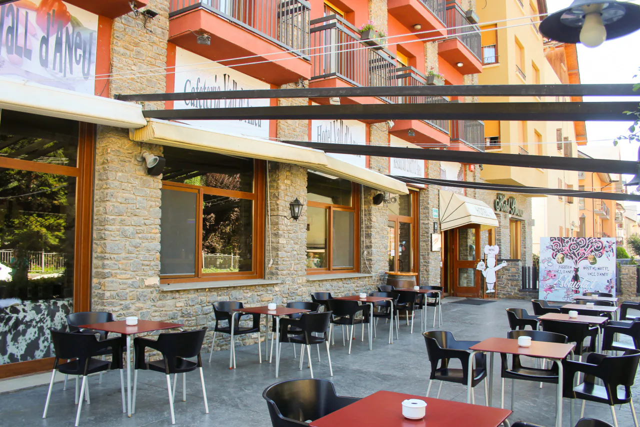 Les taules de la terrassa al carrer, amb el cartell de la pizzeria